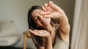 Happy Woman Holding Pill Close to Camera